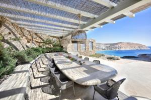 długi stół i krzesła na patio z widokiem na ocean w obiekcie Villa Serenity w mieście Mykonos