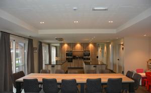 a conference room with a table and chairs and a kitchen at Duins Genot 5 star Holiday Homes 30p & 40p - Indoorpool & Wellness in Jabbeke