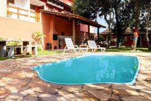 a swimming pool with chairs and a table and a building at Casa com piscina a 350m da praia em Boiçucanga in Boicucanga