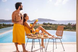 a man and woman sitting at a table with food and drinks at Elounda Palm Hotel & Suites in Elounda