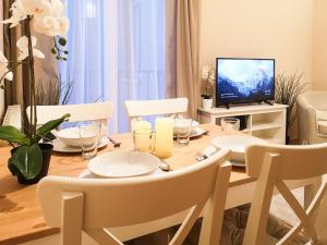 mesa de comedor con sillas blancas y TV en FilinHome Papa Suite 3, en Novi Sad