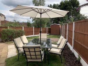 a table and chairs with an umbrella in a backyard at NEW Luxurious Modern Large 3 Bed House - Sleeps Up to 10 Guests - Sky Ultra HD, Sky Movies, Netflix, Disney Plus in Mansfield