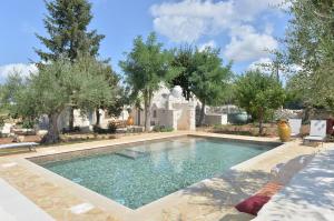 een zwembad in een tuin met bomen bij I Trulli del Tempo in Martina Franca