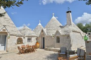 een stenen gebouw met stoelen en tafels ervoor bij I Trulli del Tempo in Martina Franca