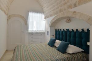 een slaapkamer met een groot bed met een blauw hoofdeinde bij I Trulli del Tempo in Martina Franca +38 foto's