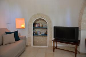 een woonkamer met een bank en een flatscreen-tv bij I Trulli del Tempo in Martina Franca