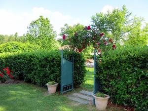 a garden with roses on a gate and two pots at Apartment Cascina Virginia-3 by Interhome in Vigliano d'Asti