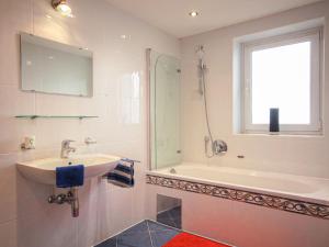 łazienka z umywalką, wanną i oknem w obiekcie Apartment Aktiv-3 by Interhome w mieście Huben