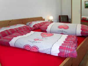 2 Betten mit roten und weißen Steppdecken drauf in der Unterkunft Apartment Aktiv - HBN221 by Interhome in Huben