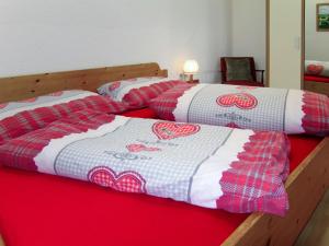 dwa łóżka z czerwoną i białą kołdrą na nich w obiekcie Apartment Aktiv-2 by Interhome w mieście Huben