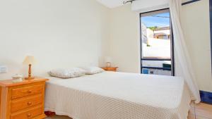 a white bedroom with a bed and a window at 1 Monts - Llafranc in Llafranc