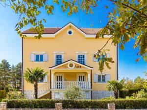 uma grande casa amarela com uma varanda em Apartment Villa Anna - JAD113 by Interhome em Jadranovo