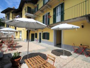 two white umbrellas and tables and chairs in front of a building at Apartment Tiffany by Interhome in Germignaga