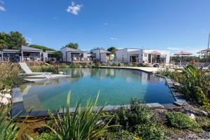 une grande piscine d'eau avec des maisons en arrière-plan dans l'établissement Lodges de Camargue, à Port-Saint-Louis-du-Rhône