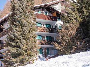 un hôtel dans la neige entre deux arbres dans l'établissement Apartment Hubertus-1 by Interhome, à Zermatt