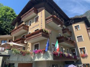 a building with flowers and balconies and flags on it at Hotel Genzianella in Chiesa in Valmalenco