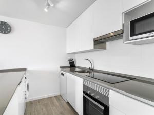 eine weiße Küche mit einer Spüle und einer Mikrowelle in der Unterkunft Apartment Camporroso Village by Interhome in Cala de Finestrat
