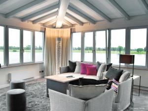 a living room with a couch and chairs and windows at Zollenspieker Fährhaus in Hamburg