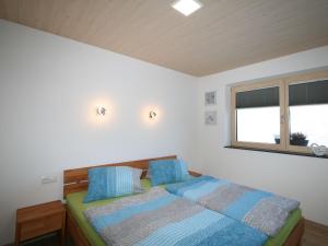 a bedroom with a bed with blue pillows and a window at Apartment Kirchler by Interhome in Hippach