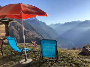 dos sillas y un paraguas en la cima de una montaña en Holiday Home Rustico Bel Panorama by Interhome en Malvaglia