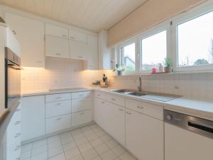 een keuken met witte kasten, een wastafel en ramen bij Villa Villa Kievit by Interhome in De Haan