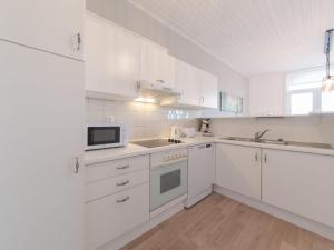 eine weiße Küche mit weißen Schränken und einer Mikrowelle in der Unterkunft Apartment Carnac Station by Interhome in De Haan