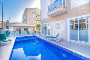 Una piscina con sillas al lado de un edificio. en Apartments Near to City Center and Beach, en Marmaris