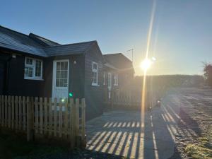 una casa con el sol brillando a través de una valla en Great Sampford B&B Sorrells farm en Hempstead