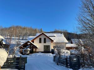 a house is covered in snow with a fence at Apartmán pri Dierach in Terchová