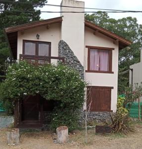 una casa bianca con porte marroni e un cespuglio di Sueño del Bosque a Santa Teresita
