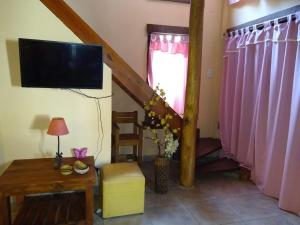 un soggiorno con tv e tende rosa di Sueño del Bosque a Santa Teresita