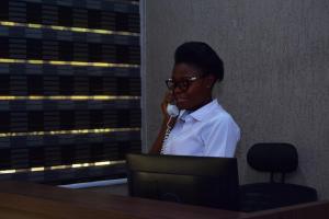 Absor Royal Hotel في Koforidua: امرأة تتحدث في جوال بجوار جهاز كمبيوتر