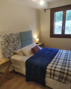 1 dormitorio con 1 cama con manta azul y ventana en Apartamento a estrenar en Villanúa en Villanúa