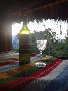 una botella de vino y una copa de vino en una mesa en Eco Albergue Azul, en Cuispes