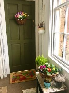 a green door with a table with flowers on it at Spacious and cozy apartment in the heart of Haddington in Haddington