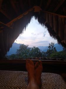 a persons feet laying on a bed looking out a window at Eco Albergue Azul in Cuispes