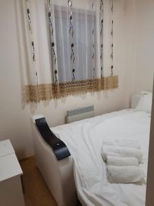 una camera con un letto bianco e una sedia nera di Apartmani Nedeljkovic Brzece Kopaonik a Brzeće