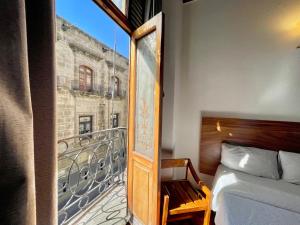 a bedroom with a bed and a view of a balcony at Hotel Frances in Guadalajara