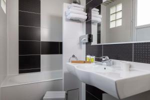 La salle de bains blanche est pourvue d'un lavabo et d'un miroir. dans l'établissement Hôtel L'Interlude, à Paris 37 autres photos