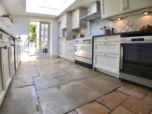 a large kitchen with white appliances and a stone floor at The Crook in Stow on the Wold