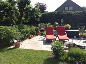 two red chairs sitting on a patio in a garden at 4 Zimmerwohnung zentrale Lage in Wendeburg