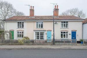 une maison blanche avec des portes bleues et une clôture dans l'établissement 2 Riverside Cottages, à Saxmundham