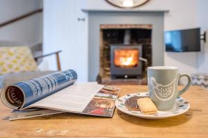 - une table avec un livre, une tasse de café et un journal dans l'établissement 2 Riverside Cottages, à Saxmundham