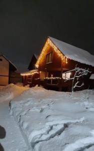 a house covered in snow with lights on it at "Карпатський краєвид" in Polyana