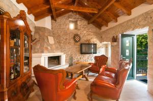 a living room with leather furniture and a stone wall at Vila M&M in Slivno