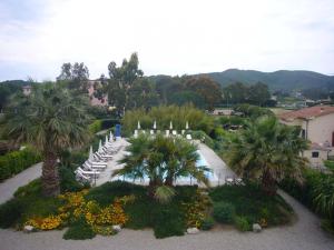 a park with chairs and palm trees and mountains at Appartamenti Le Fornaci in Marina di Campo