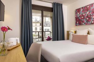 um quarto de hotel com uma cama, uma secretária e uma janela em Hotel Paris Louis Blanc em Paris
