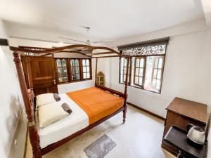 a bedroom with a bed with a wooden frame and windows at Alice in Paradise in Unawatuna