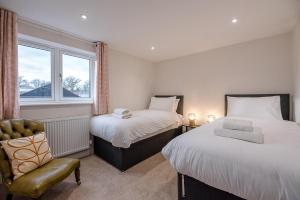1 dormitorio con 2 camas, silla y ventana en 2 The Smithy en Saxmundham