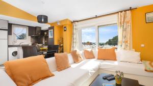 カレリャ・デ・パラフルジェリにあるAtic Mar - Calella de Palafrugellのリビングルーム(白いソファ、オレンジ色の枕付)